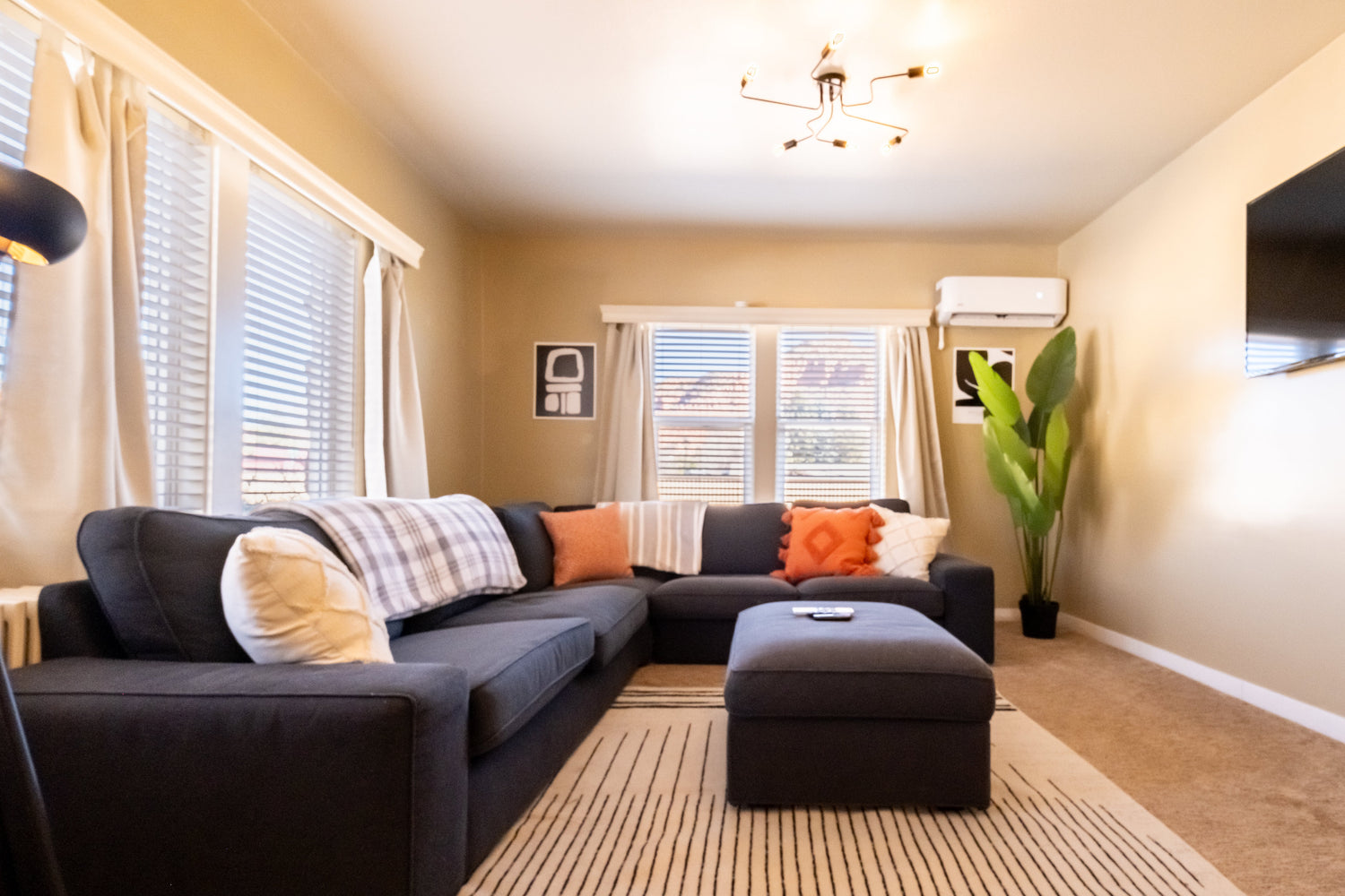 Living room with a sectional sofa, ottoman, and television.